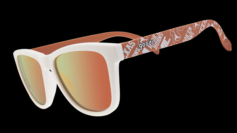 The image displays a pair of sunglasses with a white front frame and orange reflective lenses. The arms of the sunglasses are orange and decorated with University of Texas Longhorns logos