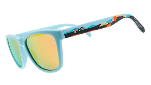 Pair of sunglasses with light blue frames and reflective yellow-orange lenses. The arms feature a vibrant tropical design with illustrations of waves and a sunset gradient.