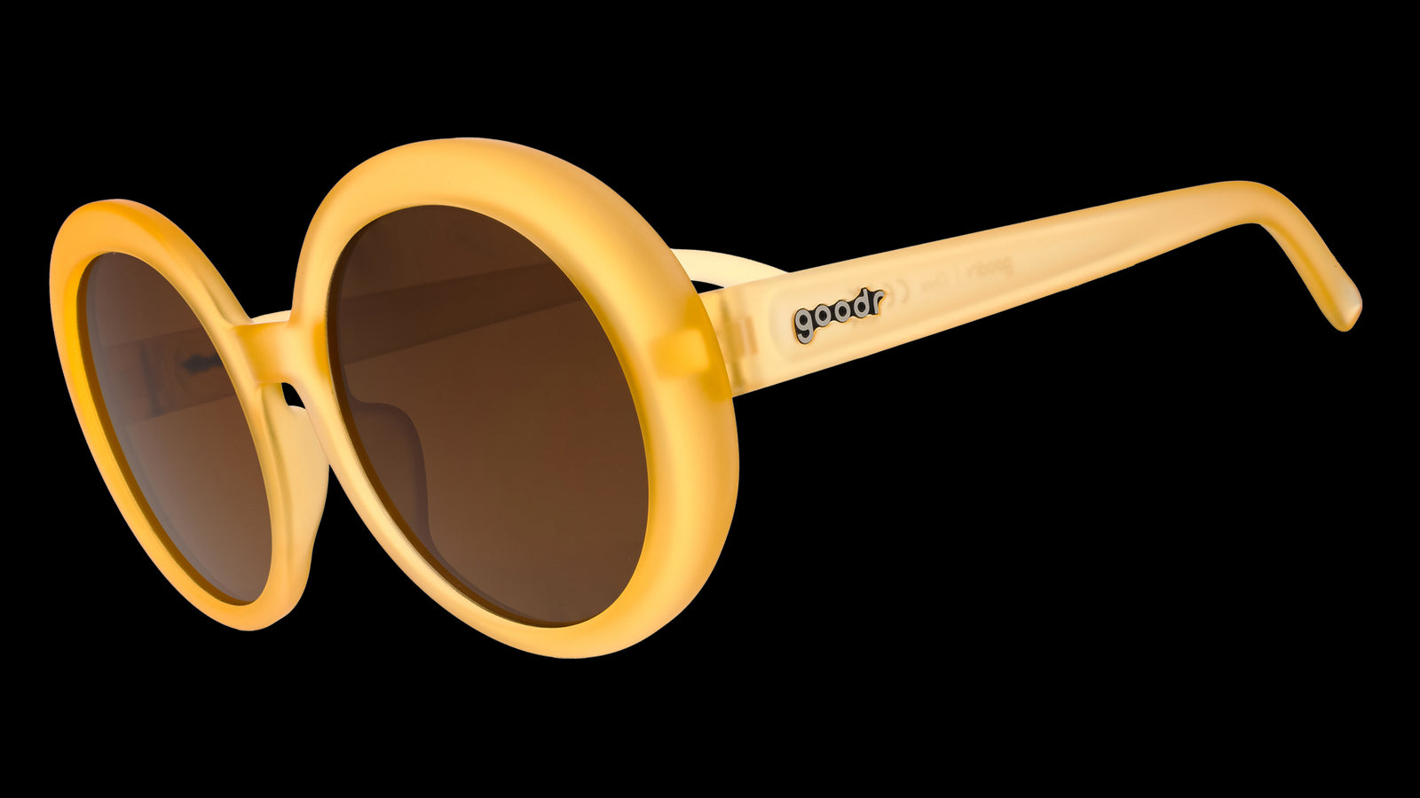 Three-quarter view of a pair of oversized, round, pale orange sunglasses with brown, non-reflective lenses.