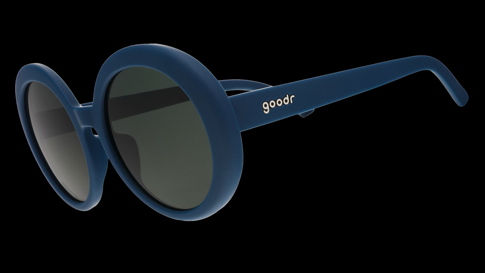 Three-quarter view of a pair of oversized, round sunglasses in a deep green with green non-reflective lenses.