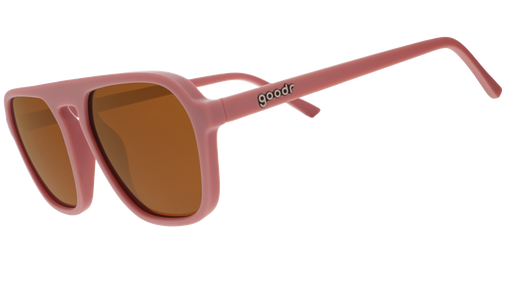 A pair of dusty rose pink goodr sunglasses with muted orange lenses on a white background.
