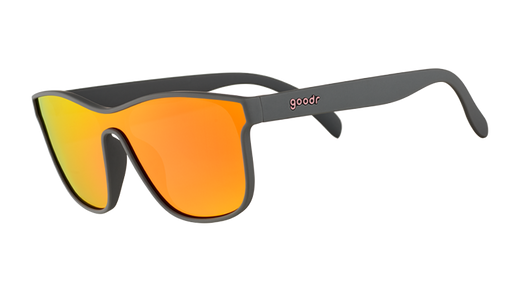 A pair of single lens goodr sunglasses with gray frames and orange/yellow reflective lenses on a white background.