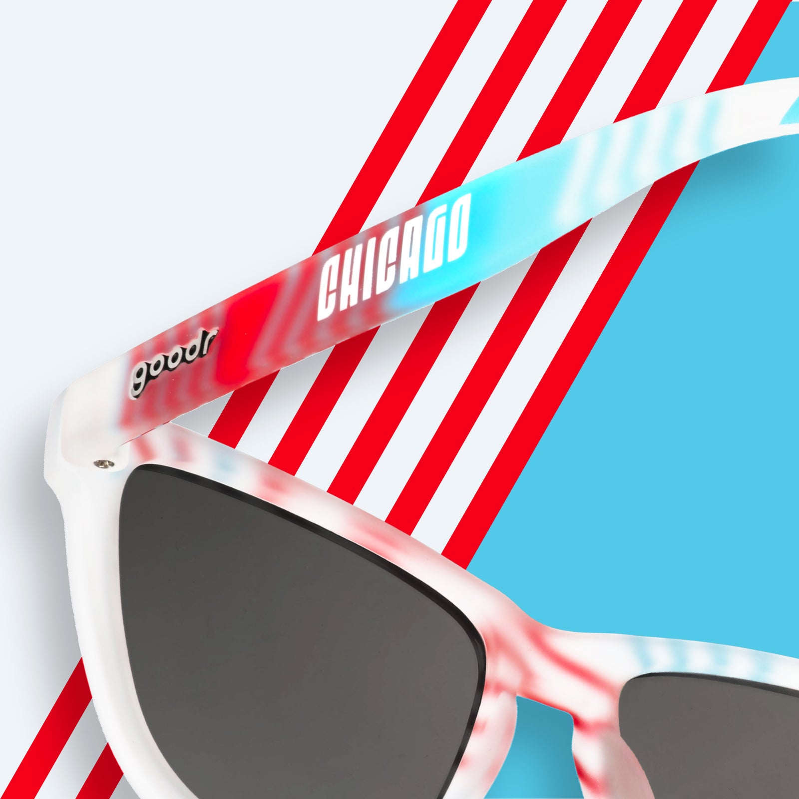 Close-up view of the back of blue and red striped sunglasses with a Chicago logo, on a striped background.