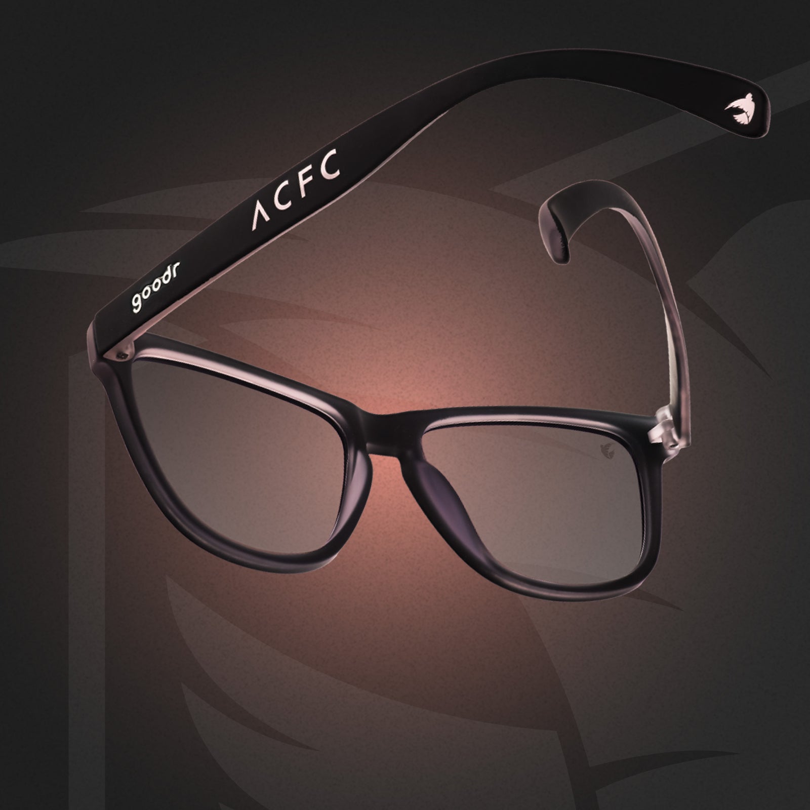 Three-quarter back angle view of black and pink sunglasses with black lenses and ACFC logo on a pink and black ACFC background.