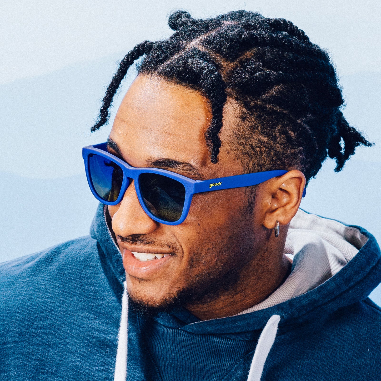 Side profile of a man posing with classic blue sunglasses with blue-yellow ocean lenses.