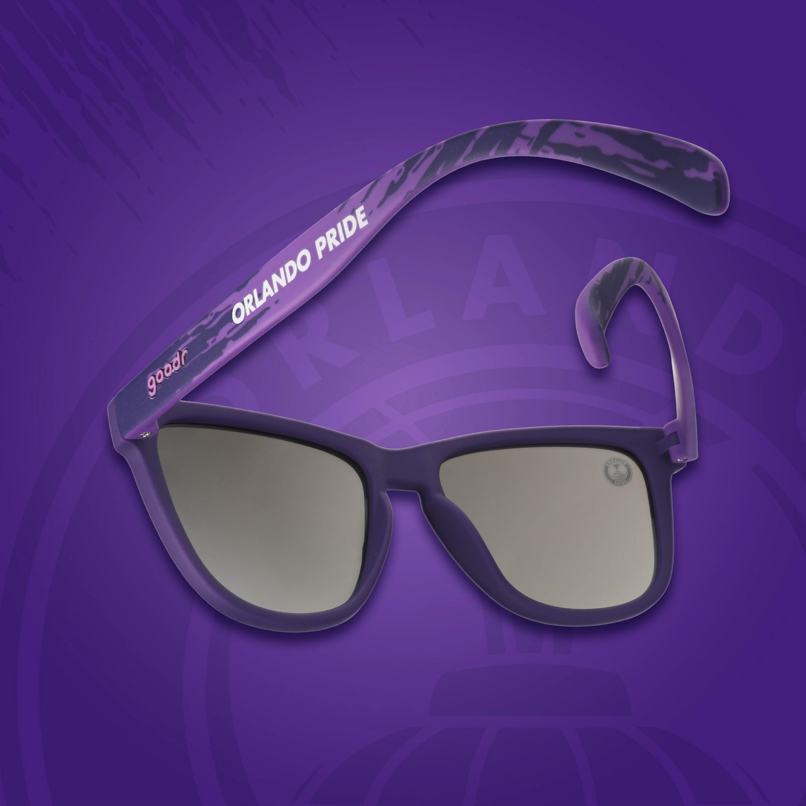 Sunglasses with 'Orlando Pride' on the arm against a purple background