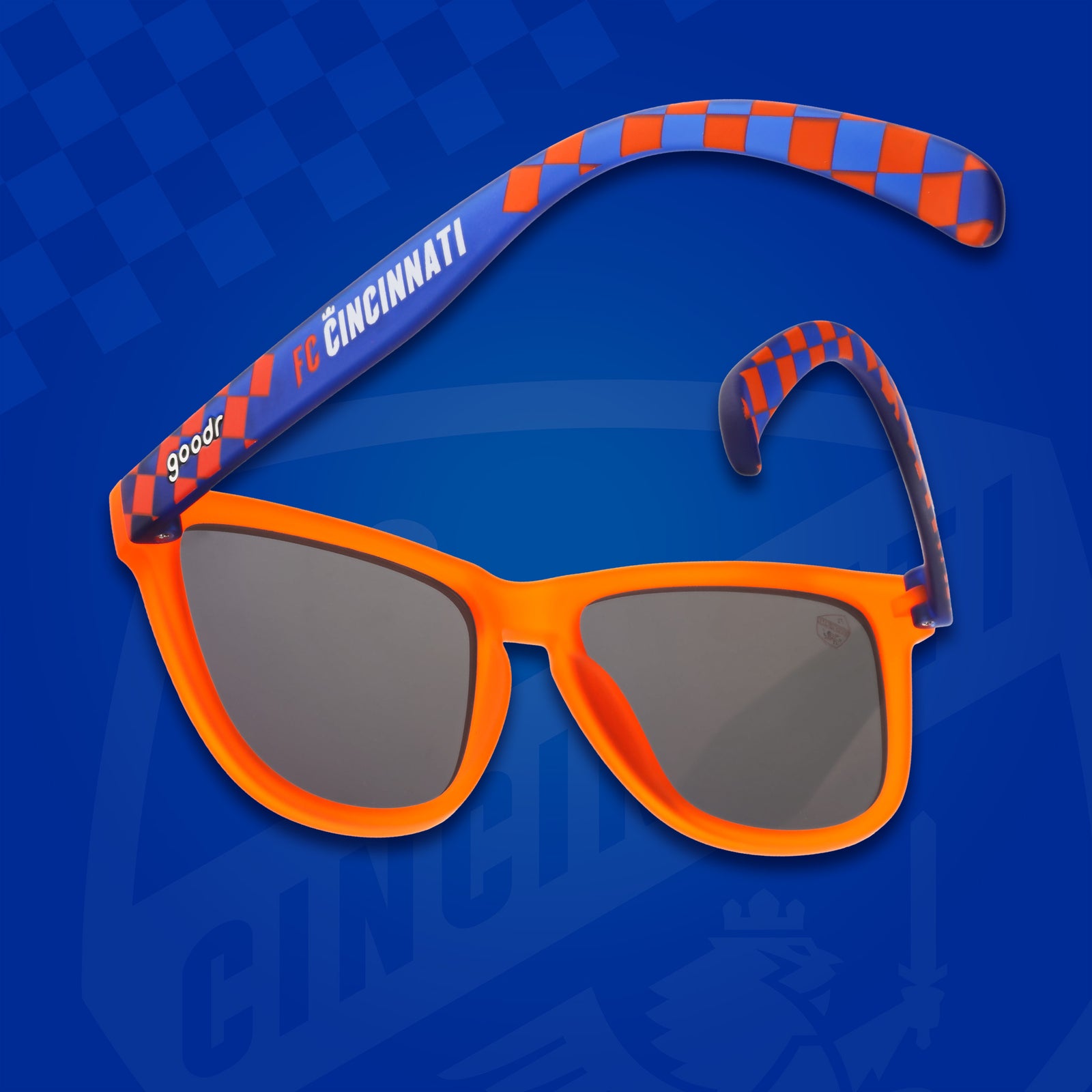 Three-quarter angle back view of FC Cincinnati shades on a blue background. Orange+blue frames. Burnt orange lenses.