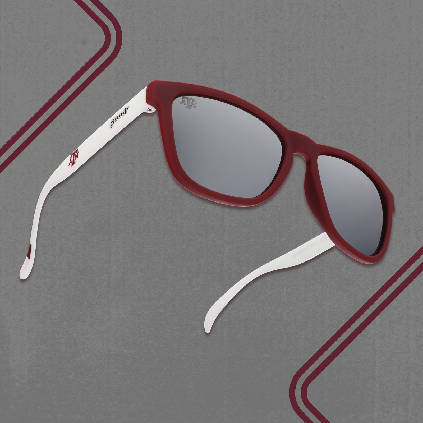 Three-quarter angle view of white and burgundy Texas A&M® Aggies™ sunglasses with chrome lenses on a gray background.