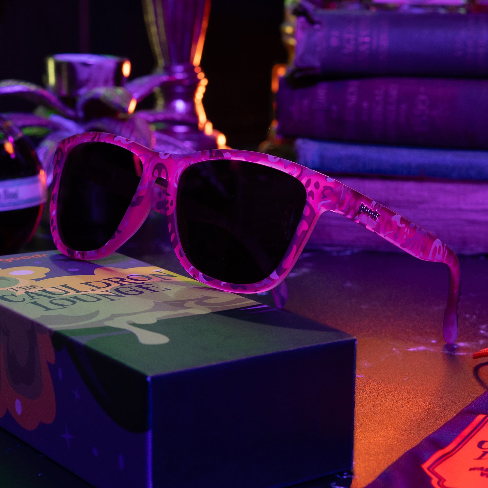 Purple sunglasses featuring a phantom print on top of a custom sunglasses box in a dimly lit room.