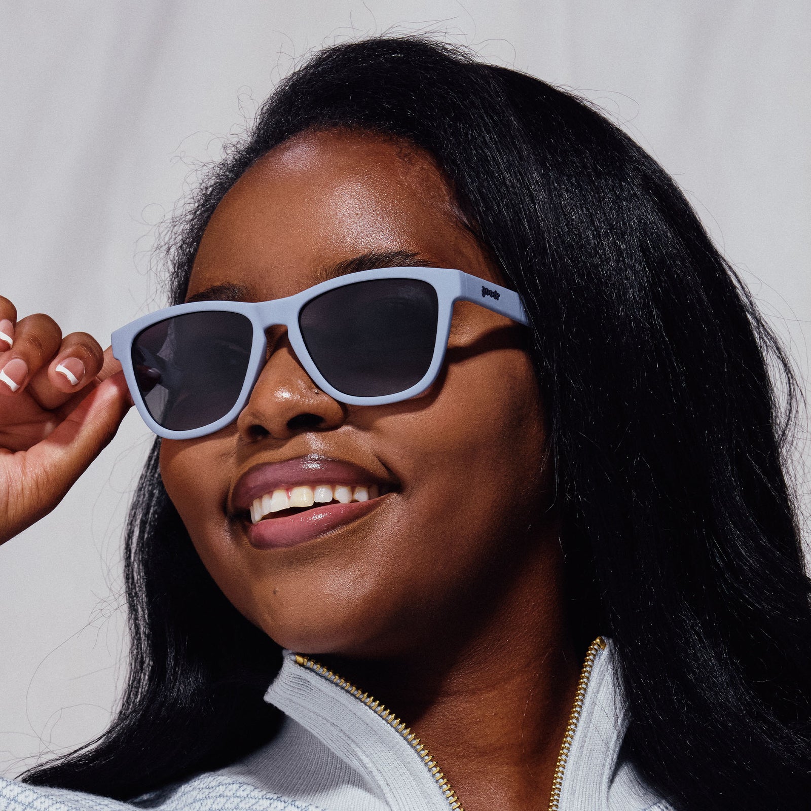 A woman wearing pair of square sunglasses with lavender frames and lenses.