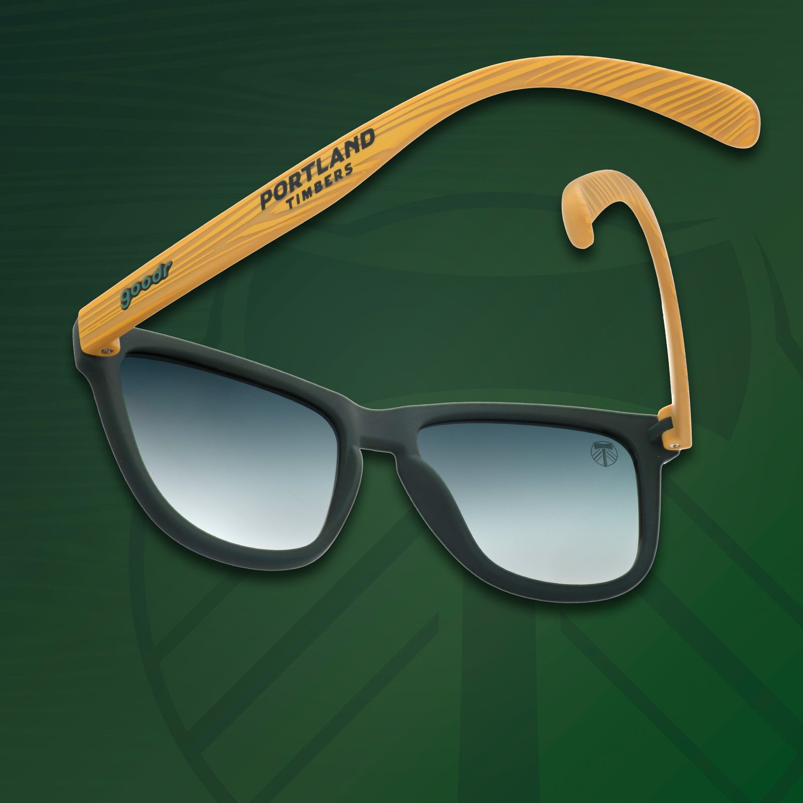 Three-quarter angle view of Portland Timbers shades tilted down with wood-style arms & green lenses on green background