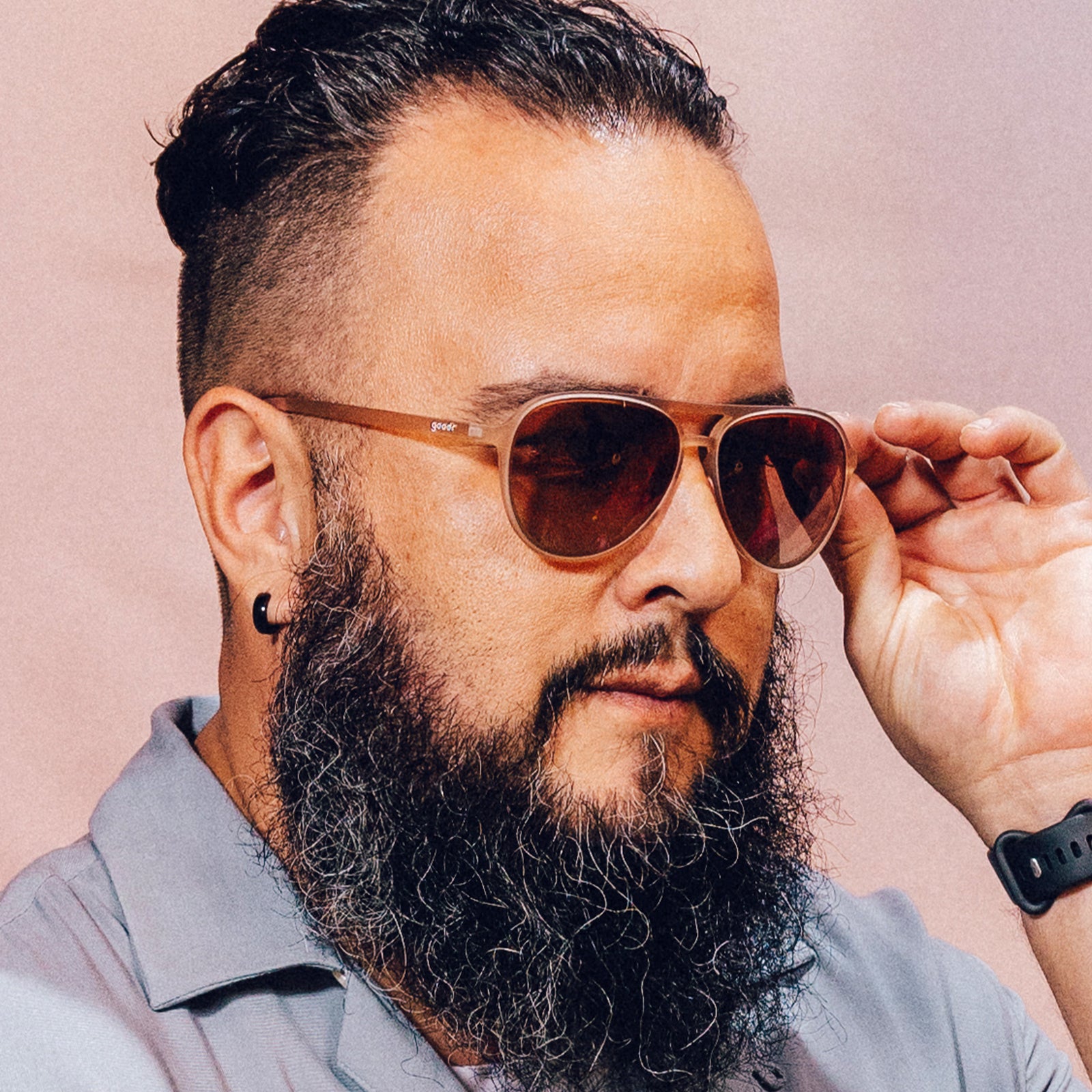 Side profile of a man posing while wearing translucent pink aviator sunglasses with rose gradient lenses.