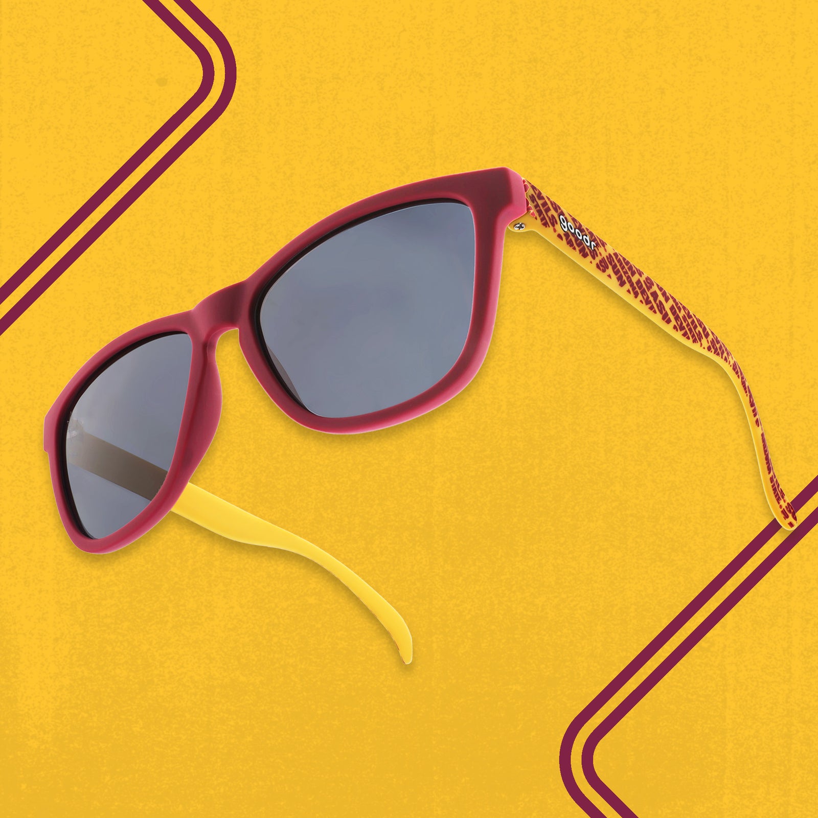Three-quarter high-angle view of dark red and yellow sunglasses with an ASU print and black lenses.