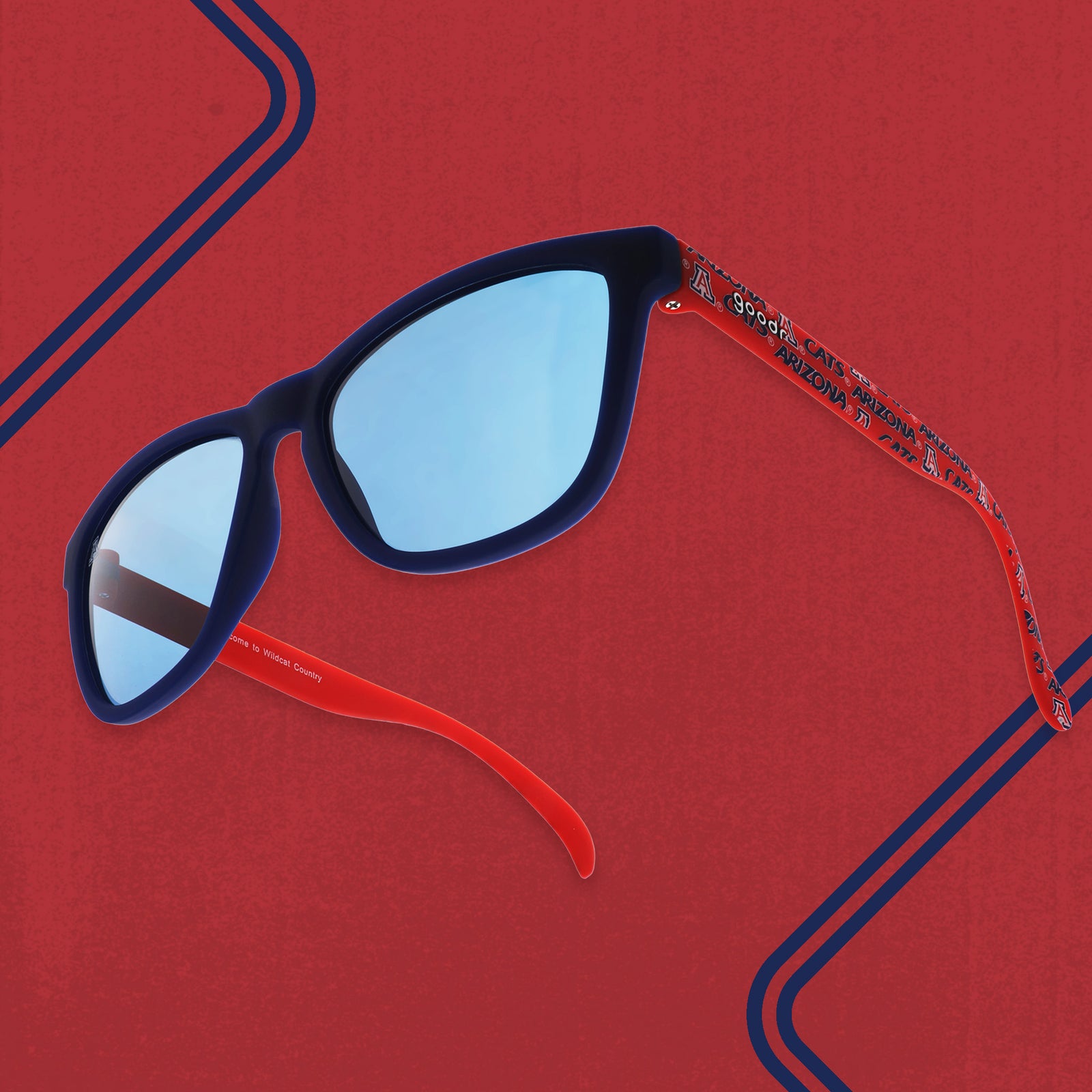 Three-quarter angle view of red and dark blue sunglasses with an Arizona print and blue lenses on a red background.