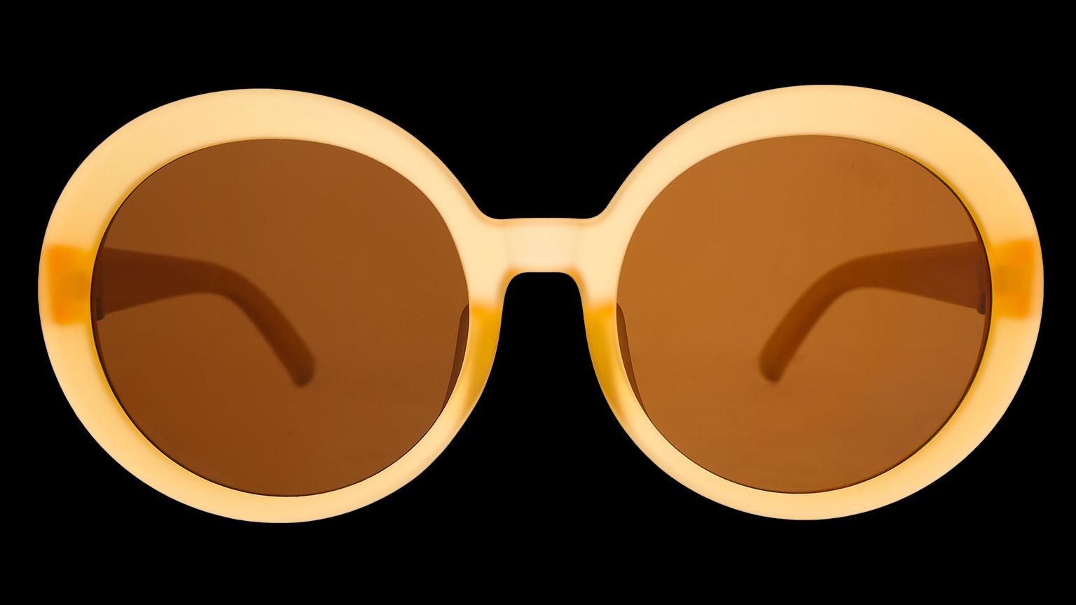 Front angle view of a pair of oversized, round, pale orange sunglasses frames with brown, non-reflective lenses.