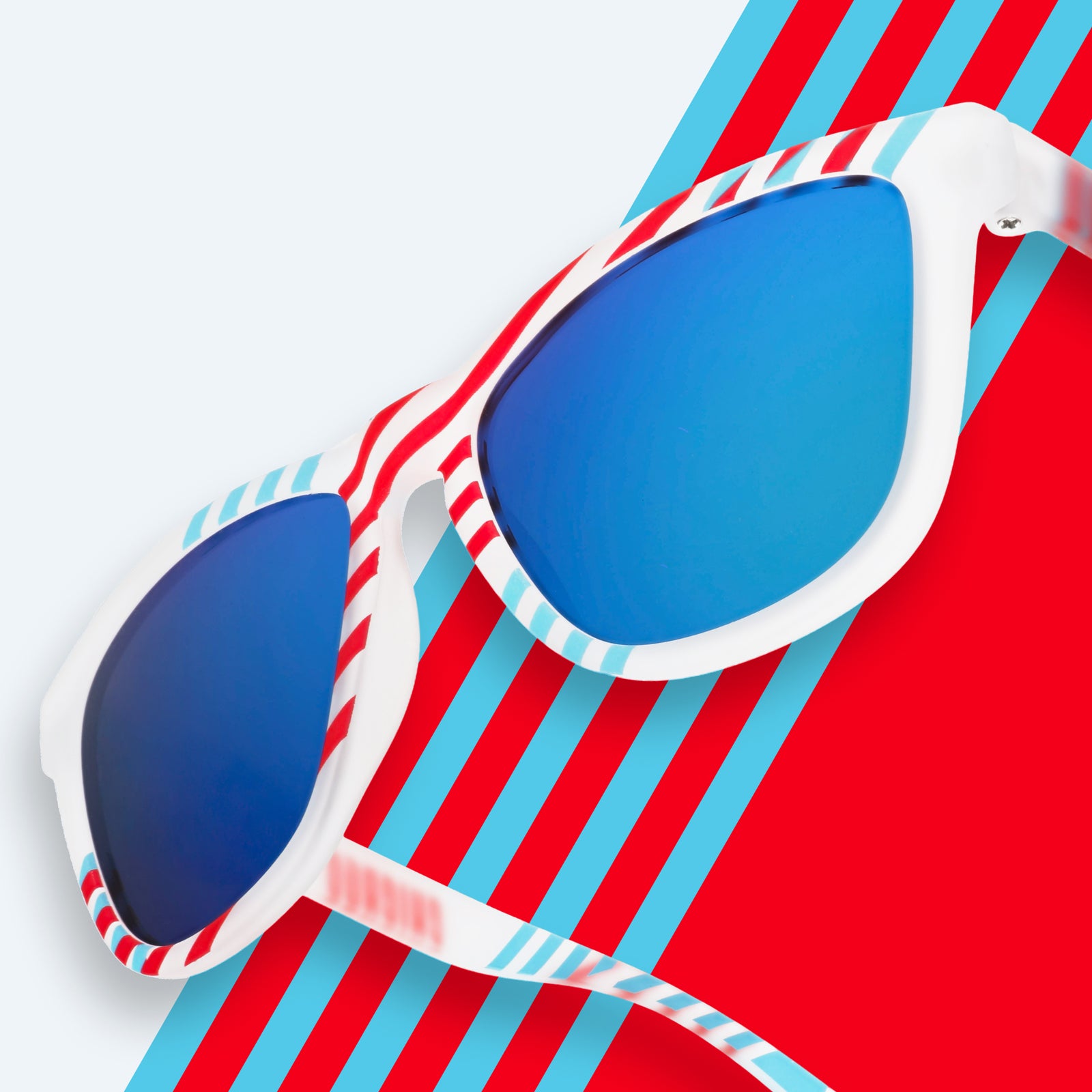 Three-quarter close-up of blue and red striped sunglasses with blue reflective lenses in front of a striped background.