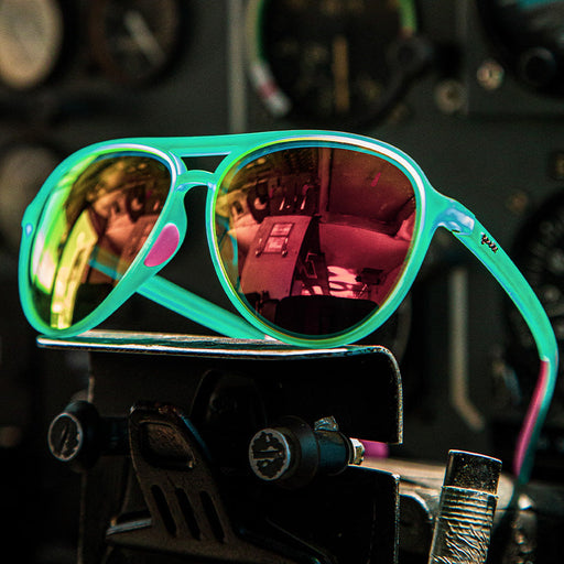 A pair of vibrant aviator-style sunglasses with light blue frames and pink accents, featuring reflective red-orange lenses.