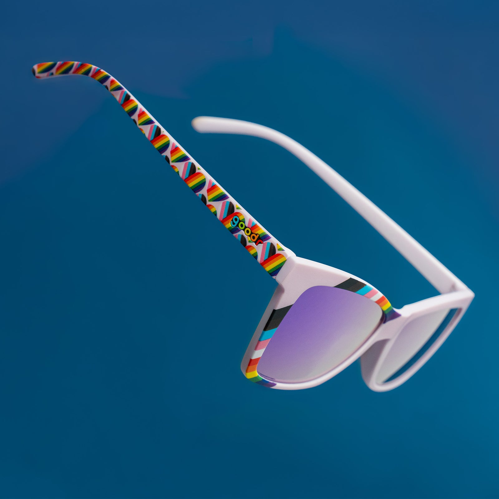 Three-quarter angle view of lilac angled cat-eye LGBTQ Pride sunglasses with purple lenses hovering mid-air facing down.