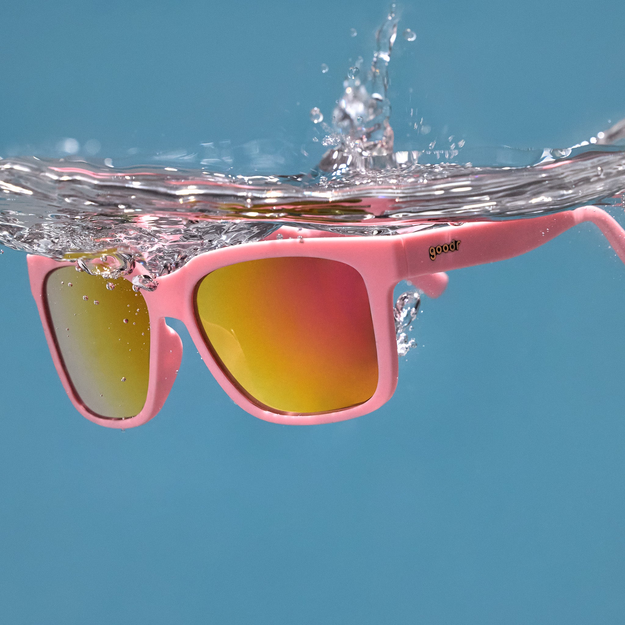 Three-quarter angle view of pink sunglasses floating in the water after being dropped.