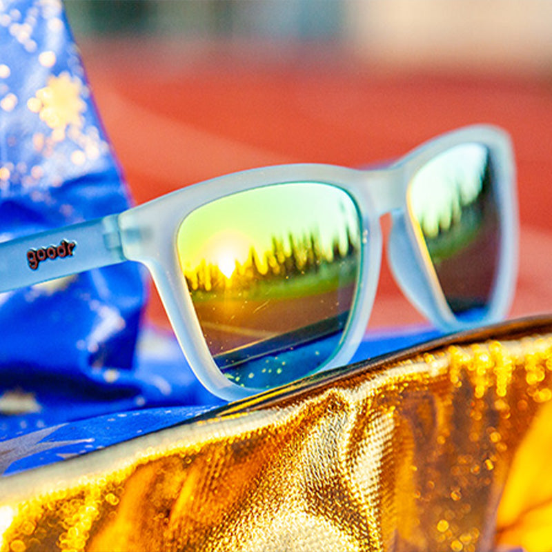 A pair of sunglasses with translucent blue frames and reflective gold lenses.
