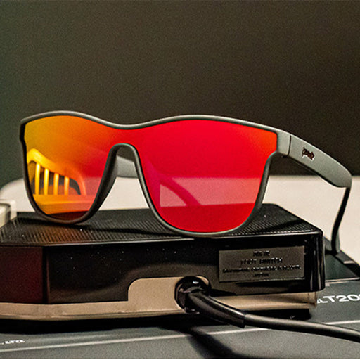 Black square shaped sunglasses with reddish-orange reflective lenses, on top of a plugged in hard drive