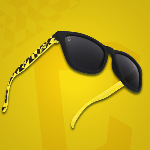 Three-quarter angle front view of MLS Columbus Crew shades on a yellow background. Black+yellow frames. Black lenses.