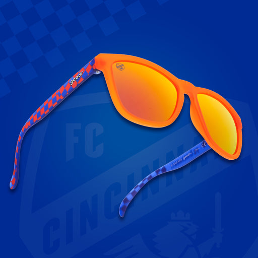 Three-quarter angle front view of FC Cincinnati shades on a blue background. Orange+blue frames. Burnt orange lenses.