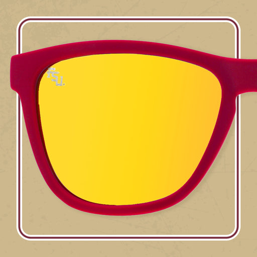 A pair of sunglasses with red frames and reflective yellow lenses. The lenses feature a small "FSU" logo in the upper left corner, representing Florida State University.