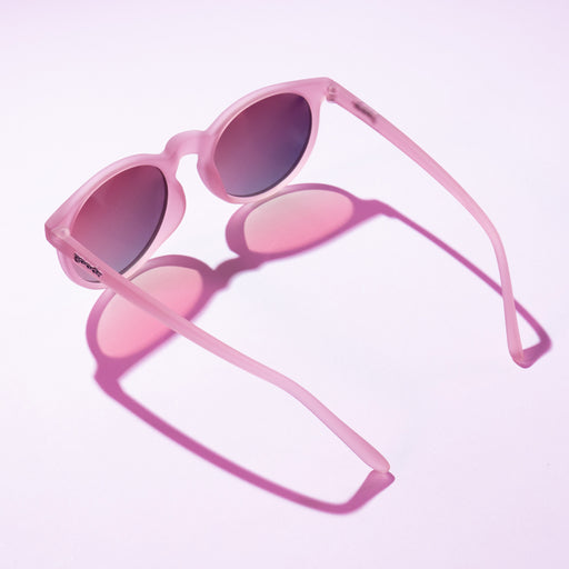 Stylish pink sunglasses with round lenses, casting a soft pink shadow on a pastel background.