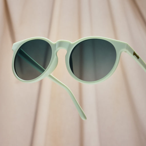 A pair of round sunglasses with mint green frames.