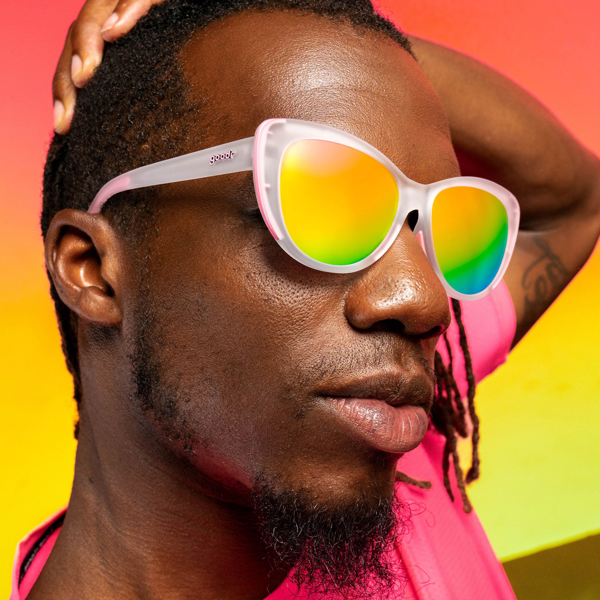 A man wearing pink cat eye sunglasses with rainbow lenses