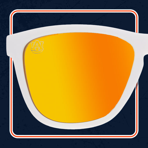 A close-up of white-framed sunglasses with bright orange reflective lenses. The left lens features a subtle "AU" Auburn University logo in the top corner, with a dark blue background framed by white and orange lines.