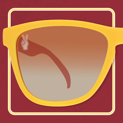 The left lens of a pair of sunglasses with mustard yellow frames, surrounded by the outline of a yellow square on a maroon background.