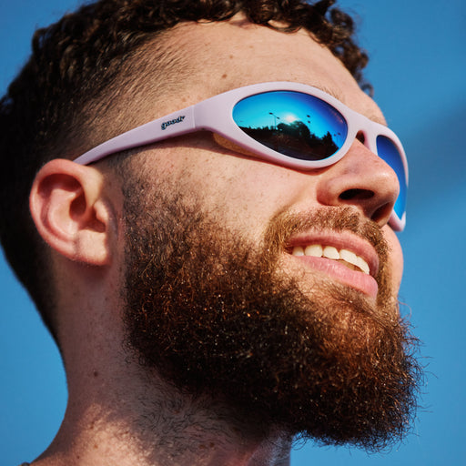 Bearded man wearing goodr sunglasses with pale pink frames and reflective blue lenses
