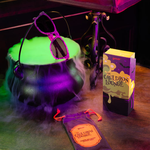 Purple sunglasses featuring a phantom print on top of a cauldron with custom sunglasses packaging in the foreground.