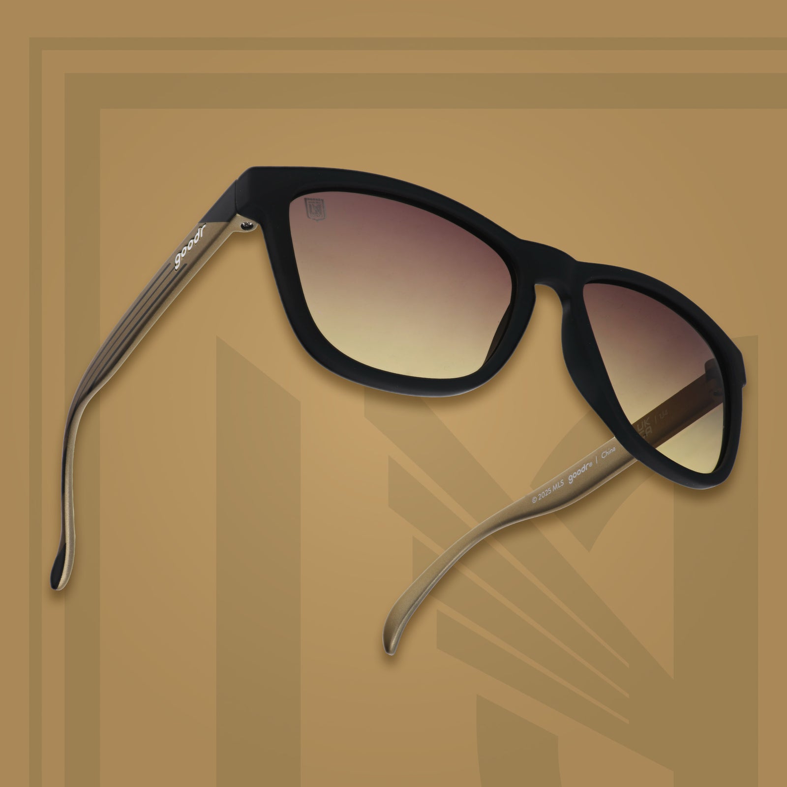 Three-quarter angle view of LAFC shades tilted up. Black and gold frames. Gray-yellow lenses. Gray-yellow background.