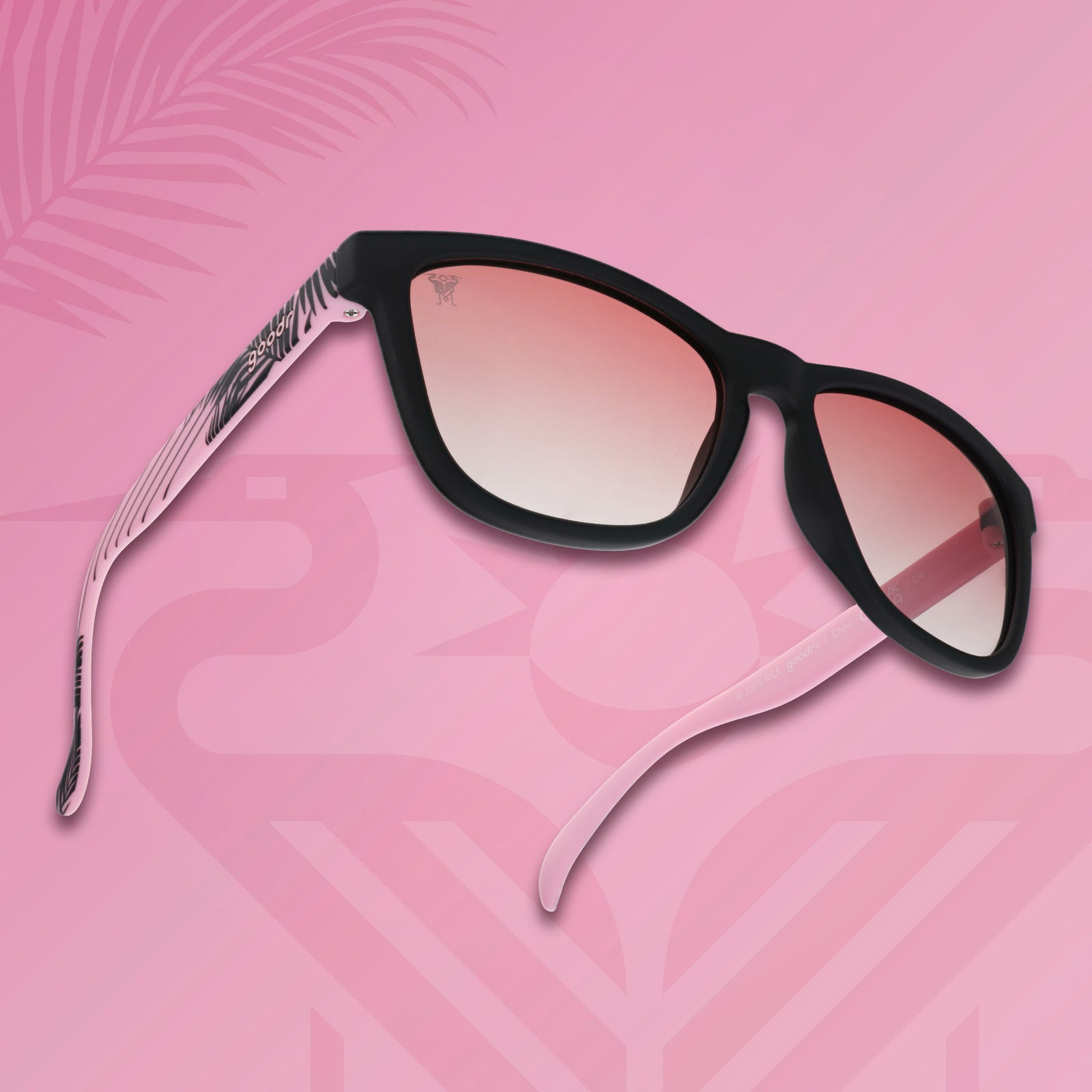 Three-quarter angle view of Inter Miami CF shades tilted up. Black and pink frames. Rose lenses. Pink background.