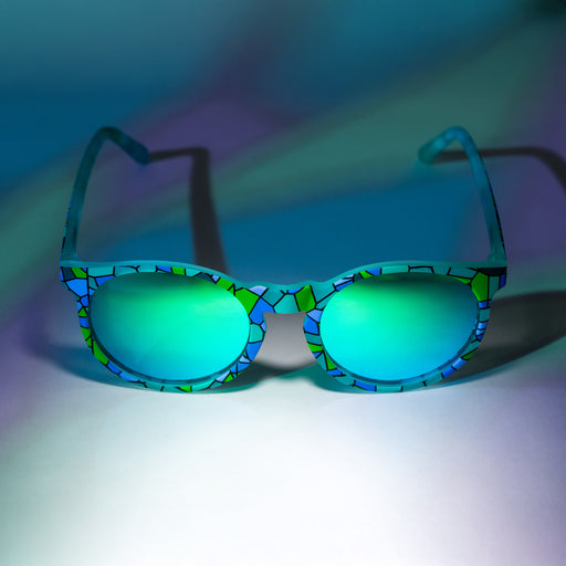 A pair of teal Circle Gs with a stained glass-inspired design sits on a white backdrop with a stained glass lighting effect.
