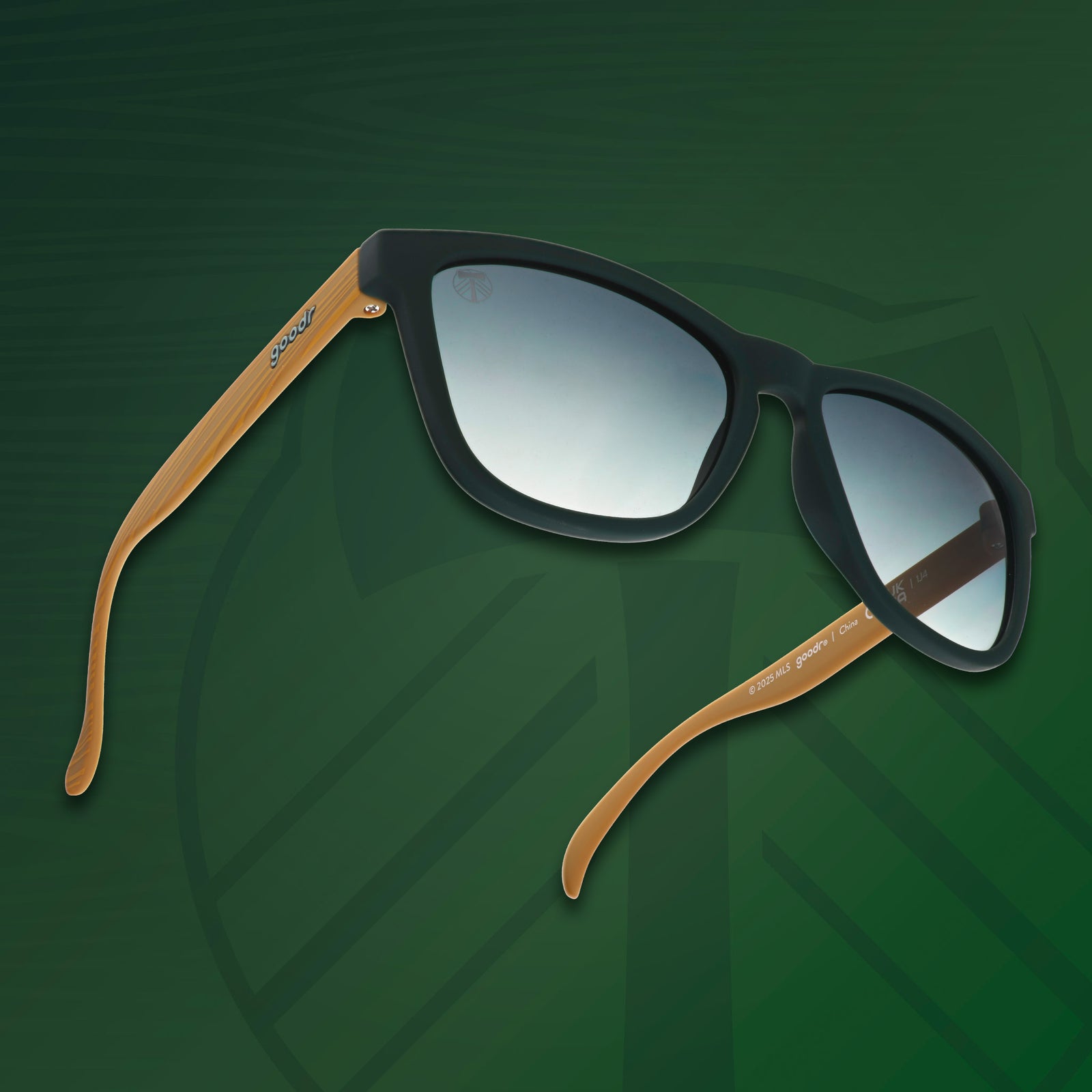 Three-quarter angle view of Portland Timbers shades tilted up with wood-style arms and green lenses on green background