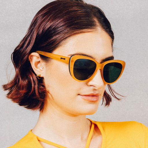 Side profile of a woman wearing translucent brown cat-eye sunglasses with green non-reflective lenses.