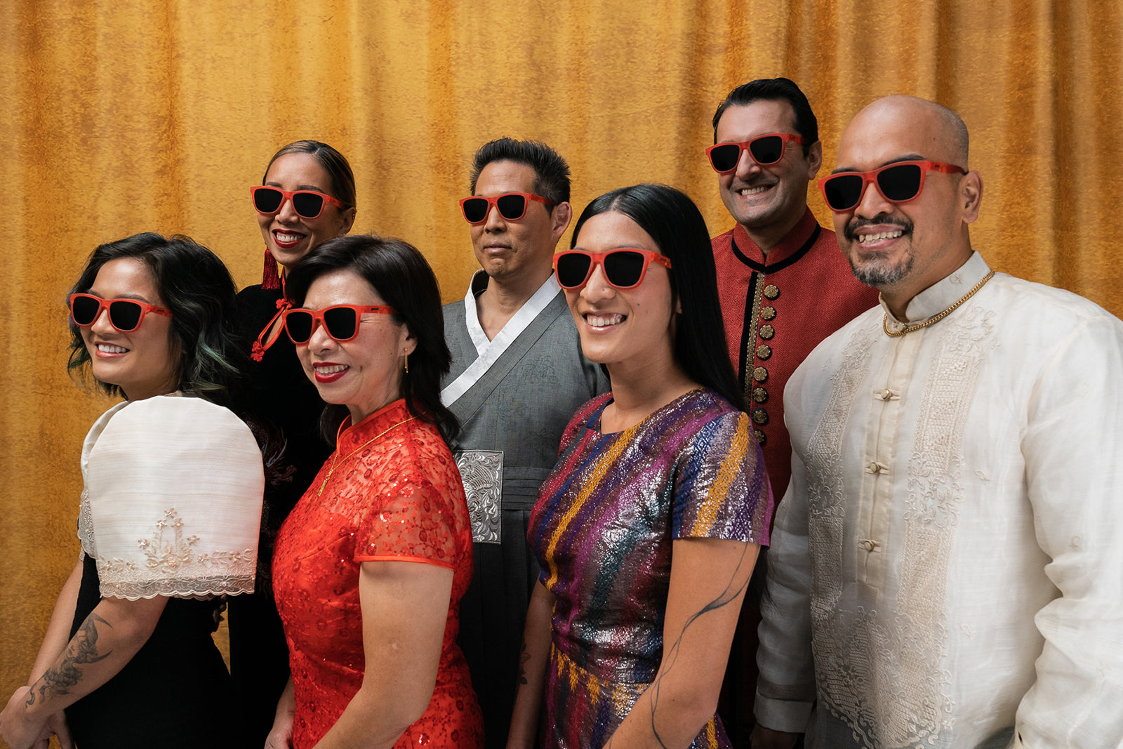 A group of people posing for a photo, presumably at a wedding, all wearing red sunglasses with black lenses