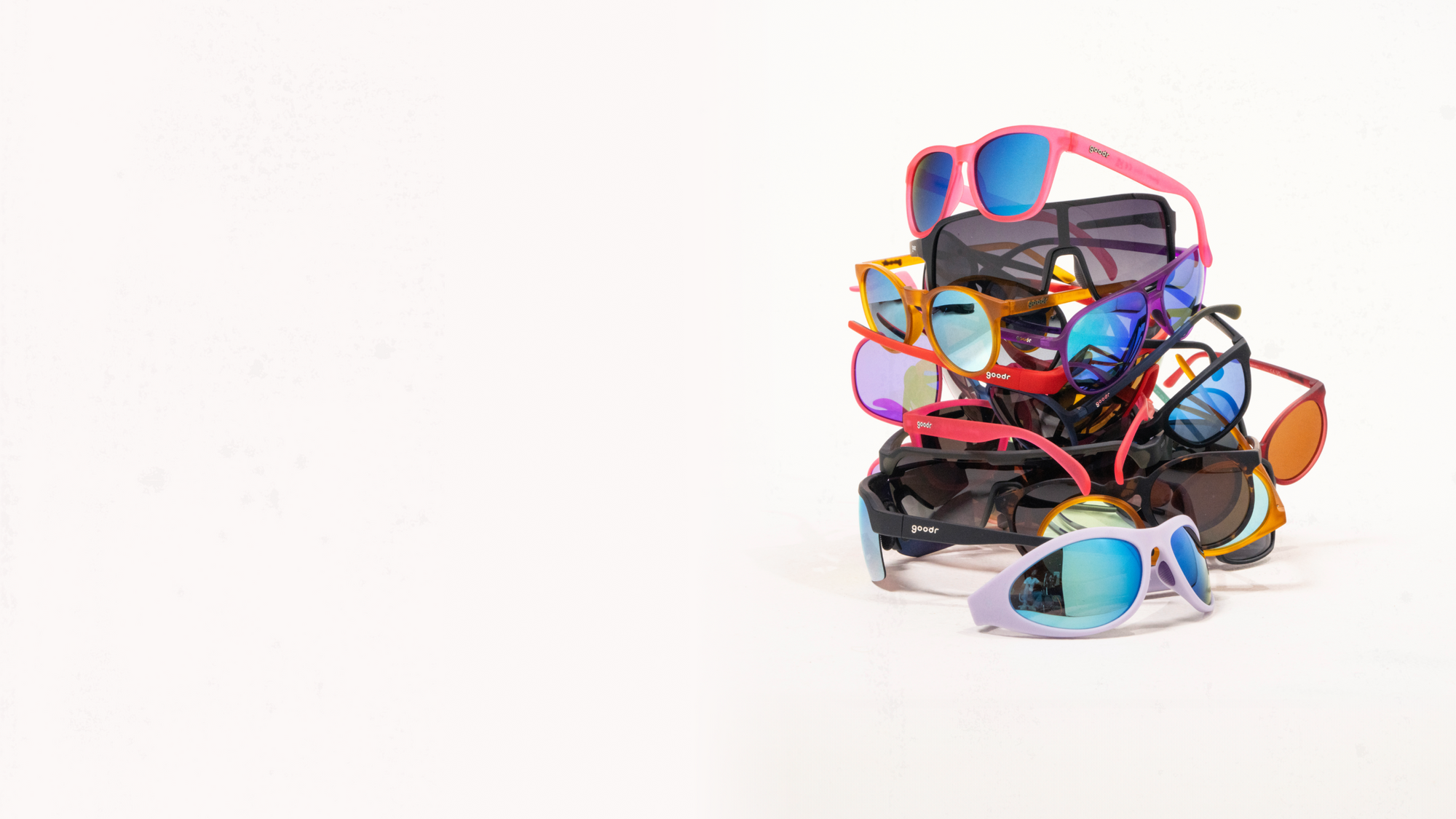 A pile of multiple pairs of sunglasses in different styles and colors.
